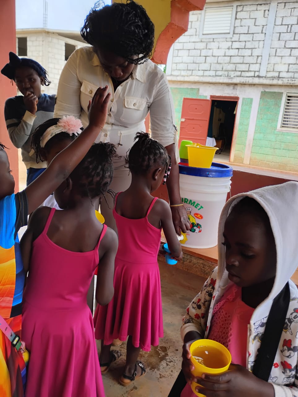 A teacher serving drinks to students at Gospel Haiti School